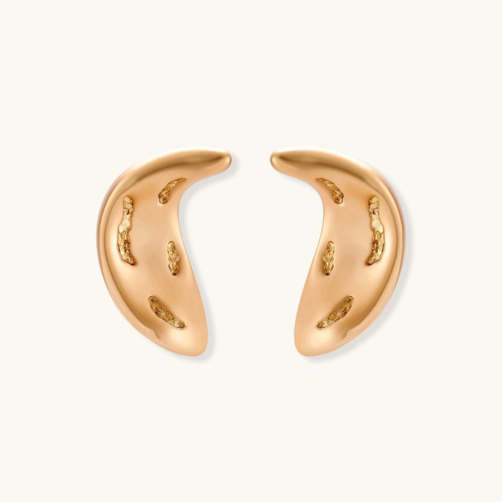 Pair of gold crescent moon-shaped stud earrings with textured surface details on cream background.