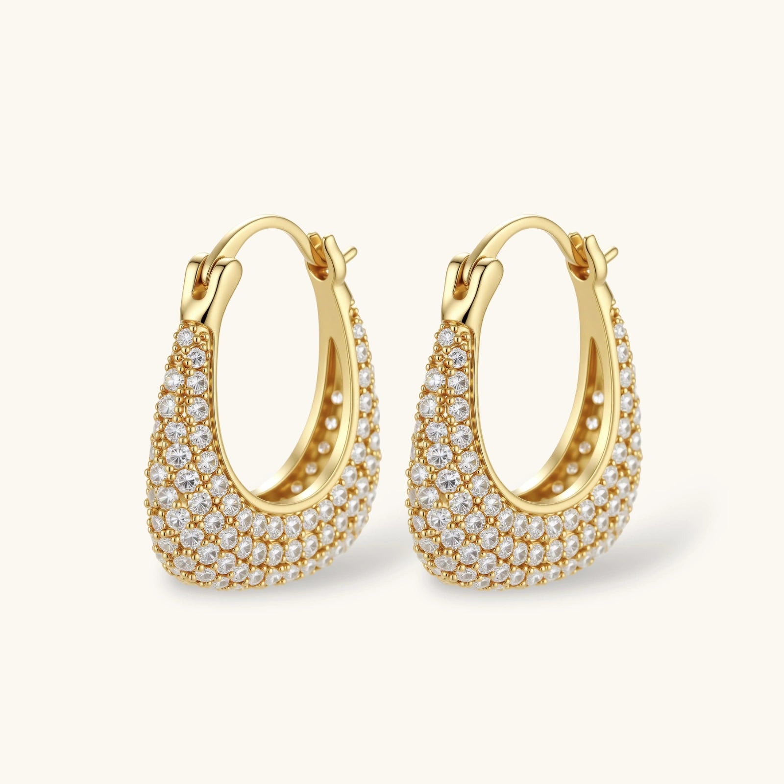 Gold-plated hoop earrings fully covered in sparkling zircon crystals with hinged closure on neutral background