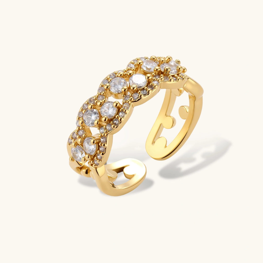 Adjustable gold-plated ring with multiple crystal clusters in intricate chain design on cream background.