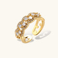 Adjustable gold-plated ring with multiple crystal clusters in intricate chain design on cream background.