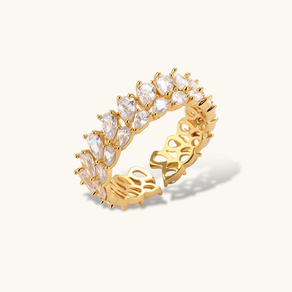 Adjustable gold-plated ring with double-row pear-shaped cubic zirconia stones in geometric pattern on cream background.